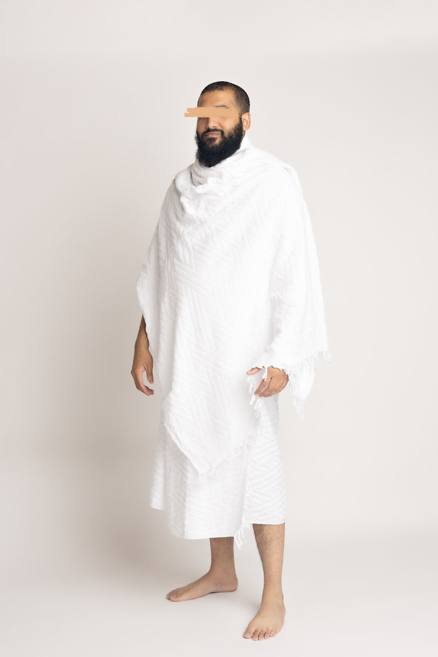 A 3/4 pose photo of a  muslim man wearing a two piece mens white ihram set from the halal caravan