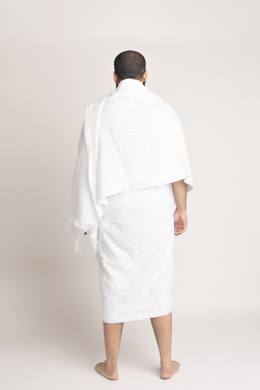 A back pose photo of a muslim man wearing a two piece mens white ihram set from the halal caravan
