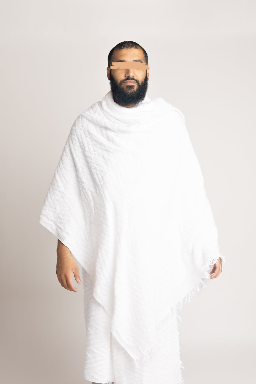 A front body shot photo of a muslim man wearing a two piece mens white ihram set from the halal caravan